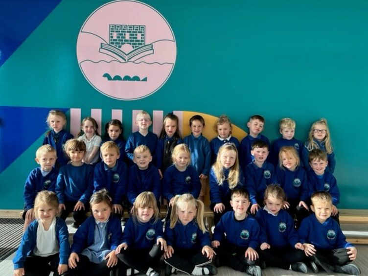 First class of 2023 at highlands and islands school Ness Castle Primary School in three rows with the crest painted above them
