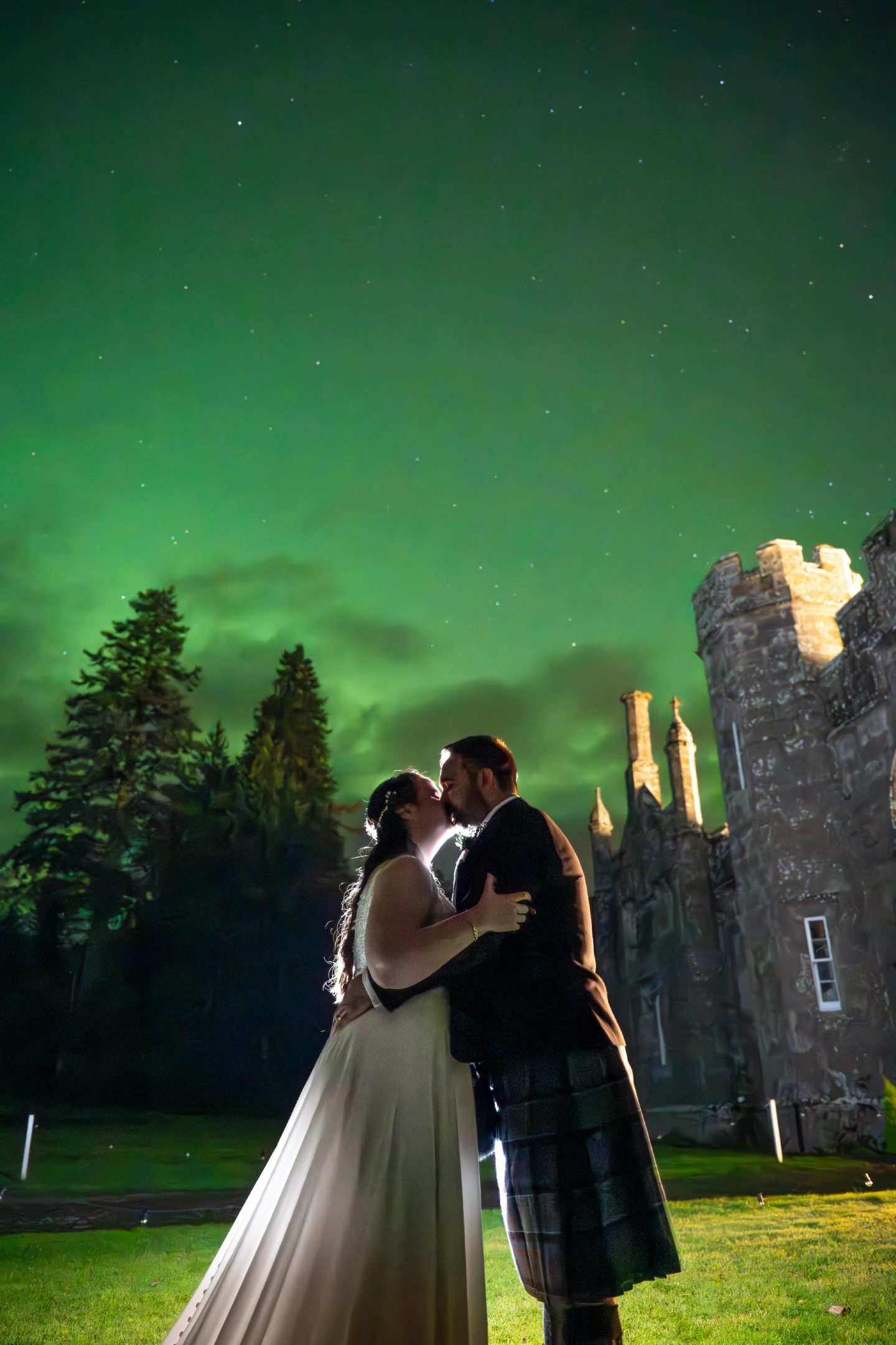 Wedding photo of Claire and Alasdair Macdonald embracing under the Northern Lights on Abercairny estate in Perthshire.