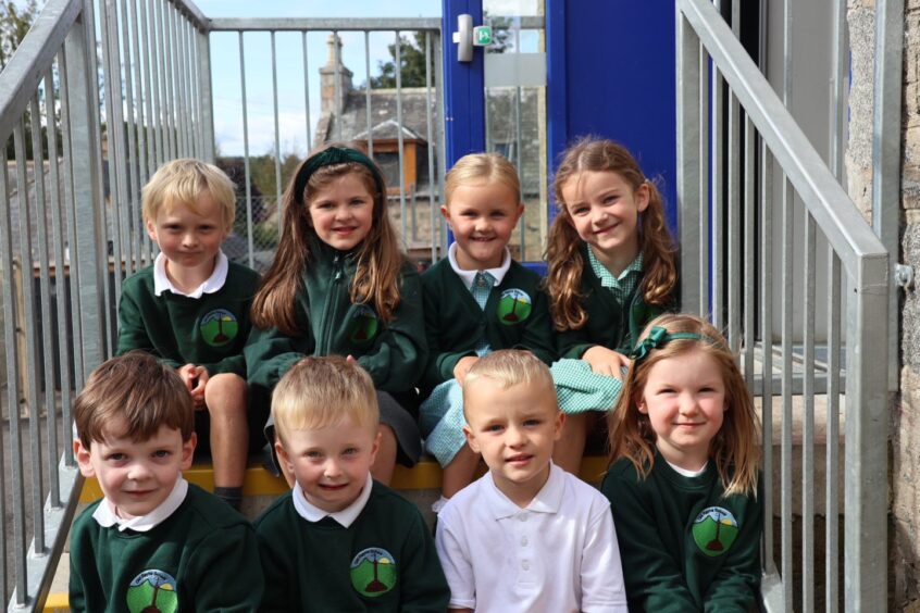 Eight pupils from Old Rayne School Primary sitting on a set of stairs outside the school