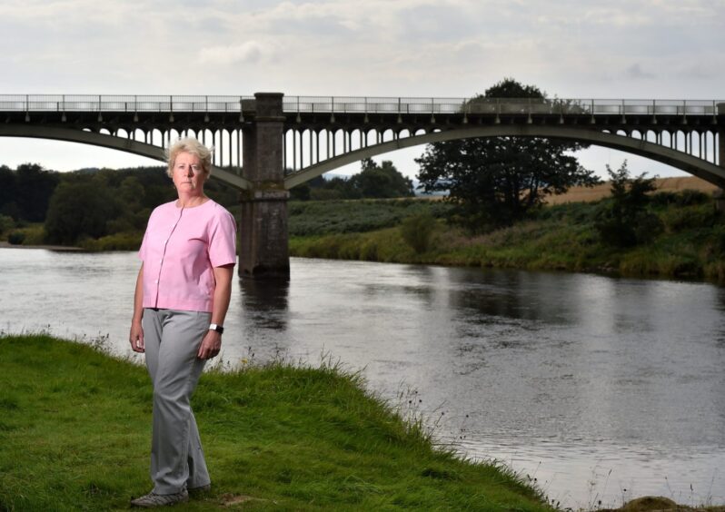 Anne Shearer standing in front of Park Bridge at side of River Dee.