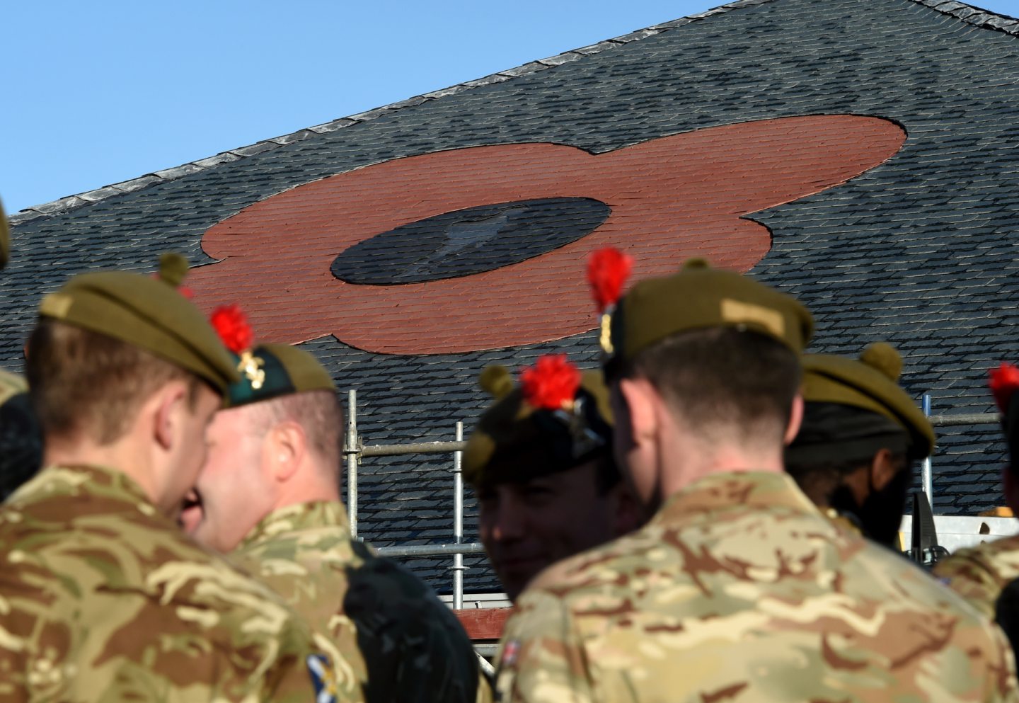 Soldiers in front of a giant poppy on the roof of The Hub in Inverness ahead of Remembrance Day.