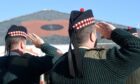 Soldiers from 3SCOTS salute a giant poppy on the roof of The Hub in Inverness