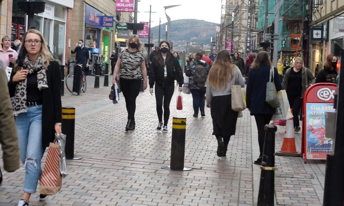 Shoppers in Inverness city centre walking around bollards. 