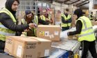 Scrum of warehouse staff over parcels on conveyor belt.