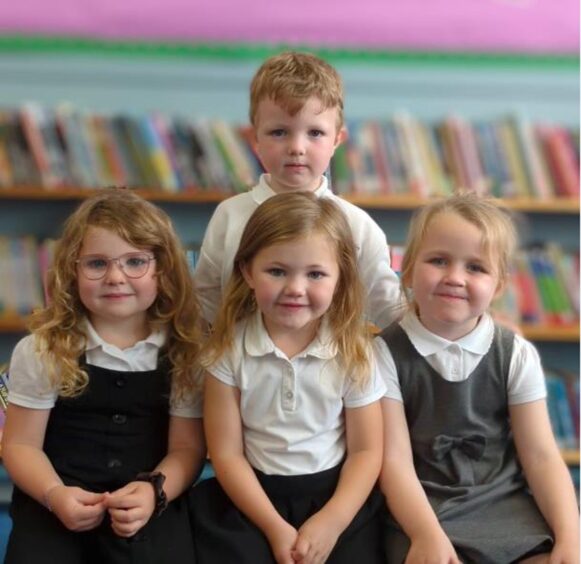 First class of 2023 at Portgordon Primary in Moray. The four children are in the library with a row of three girls at the front and one boy behind them