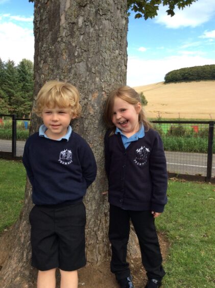 Two p1 pupils from Premnay Primary School, leaning against a tree