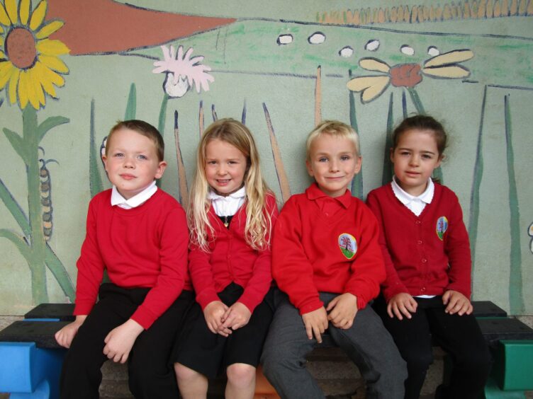 Four Redmyre School pupils sitting on a bench with a mural of flowers behind them
