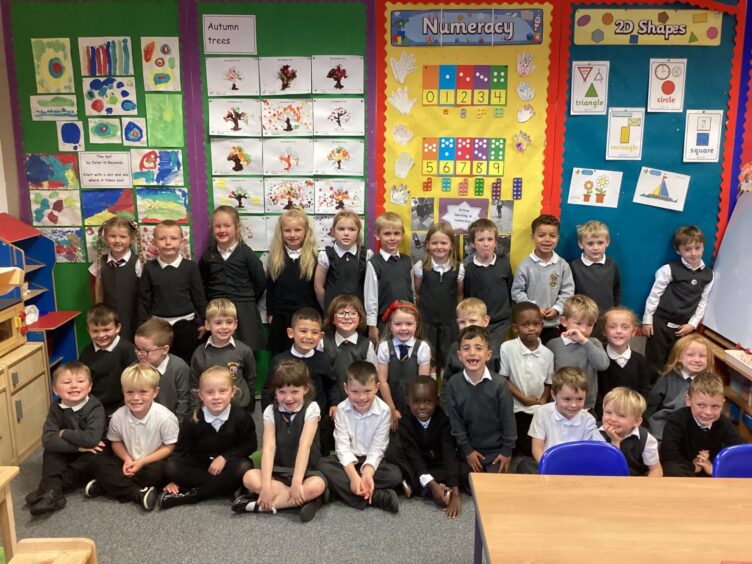 First class of 2023 at Rothesay Primary School in the Highlands and Islands. The children are in three long rows in a classroom with colourful displays behind them