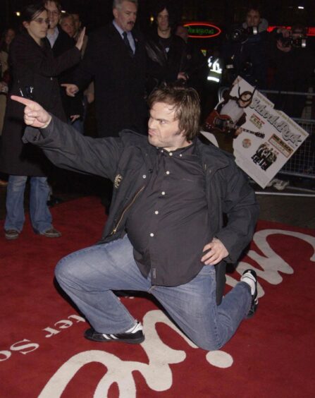 Jack Black on one knee pointing and posing on the red carpet at the premiere of School of Rock. 