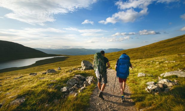 Tourist friends on a top of mountains in a Scottish Highlands. Scotland nature. Tourist people enjoy a moment in a nature.