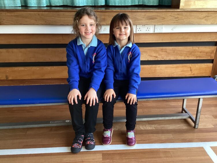 Two girls from Slains Primary School sitting on a bench in the PE hall