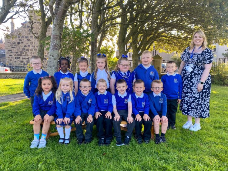 Class P1-2D at St Andrews Primary arranged in two rows outside the school with their teacher standing next to them