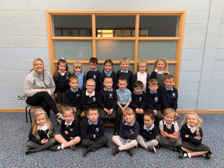 Class P1CM at Strathburn School with their teacher sitting on a chair next to them