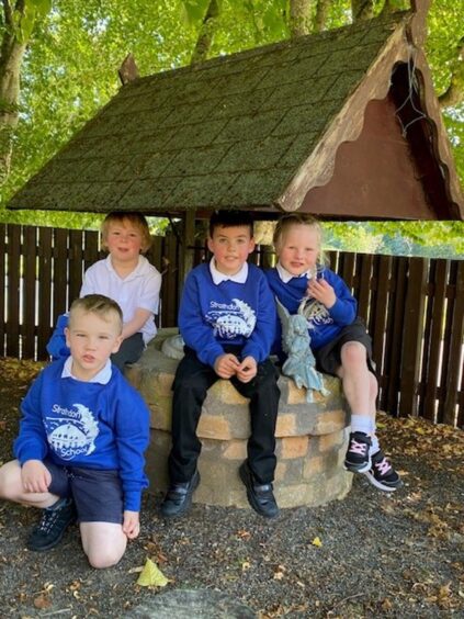 Four Strathdon Primary School pupils sitting around a well
