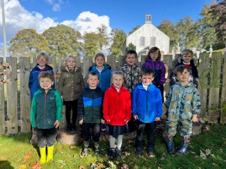First class of 2023 at Tomnacross Primary in the Highlands and Islands standing in row rows outside in colourful jackets