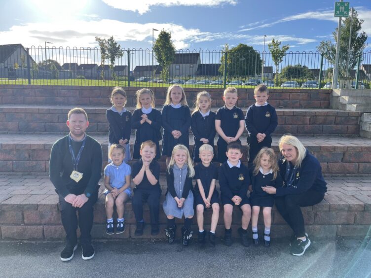 Class P1-2 outside Turriff Primary with two members of staff. They are the first class of 2023 at the aberdeenshire school