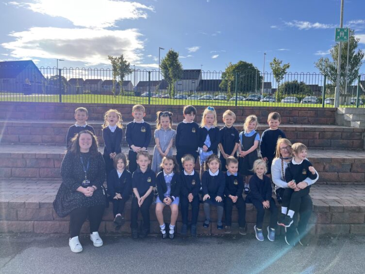 Class P1A sitting on large brick stairs outside the Turriff Primary school