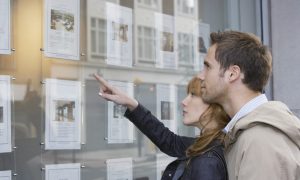 Young couple looking at window display at estate agency