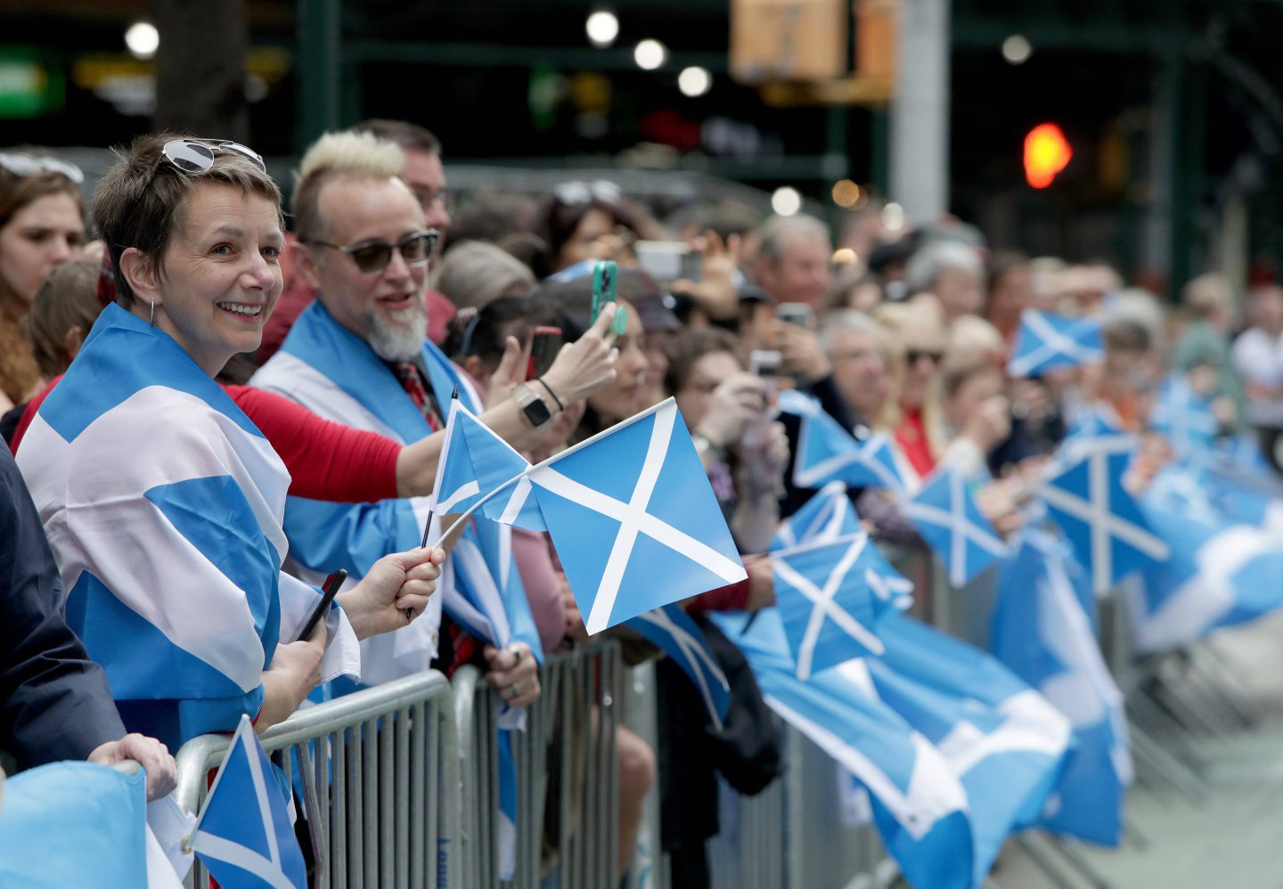 People standing waving Scotland flags.