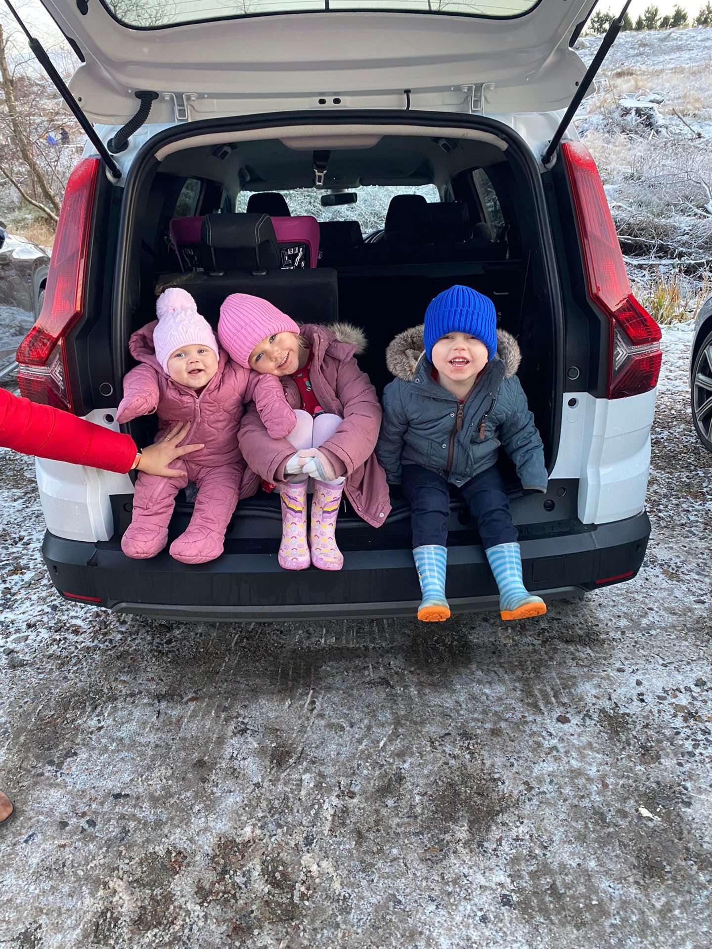 Ava, Sophie and Jack sitting on the back of a car.