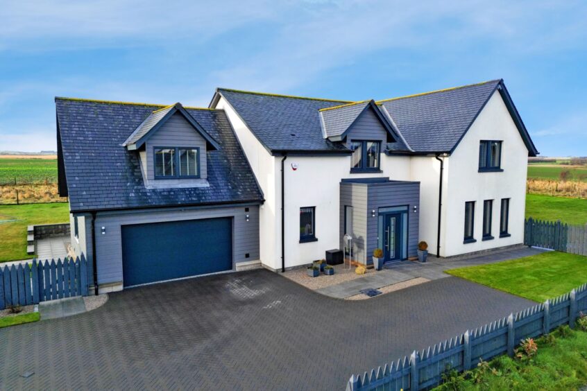 The exterior of the house, with a driveway, front lawn and garage