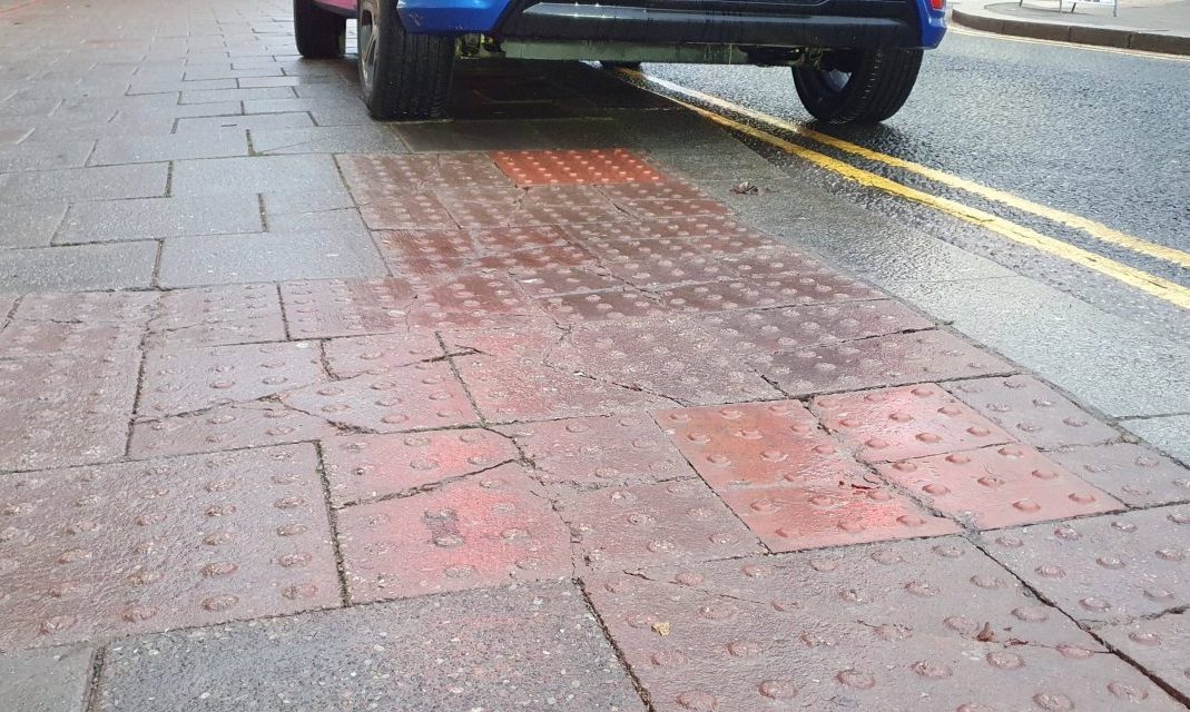 Close-up of pavement with car parked on double yellow lines. 