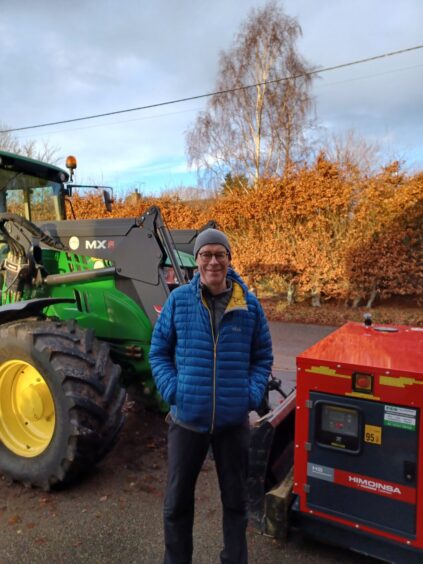 Roddy MacInnes standing next to generator and tractor.