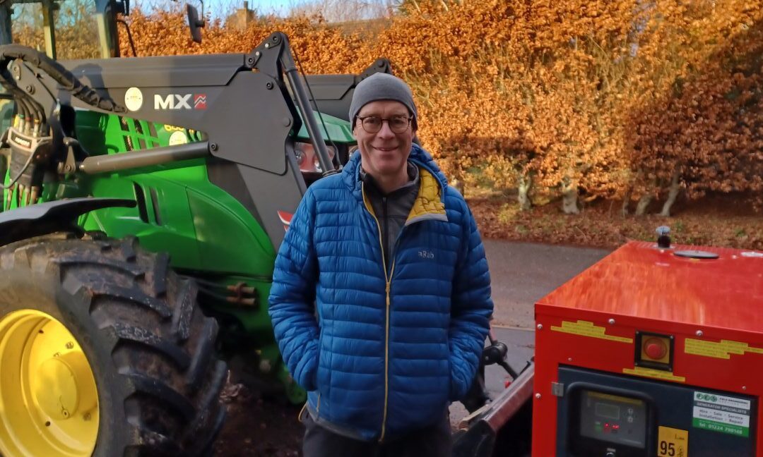 Roddy MacInnes standing next to generator and tractor.