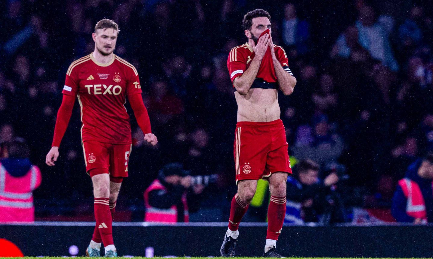 Aberdeen's Graeme Shinnie and Richard Jensen looking dejected on the pitch, Shinnie is wiping his face with his shirt