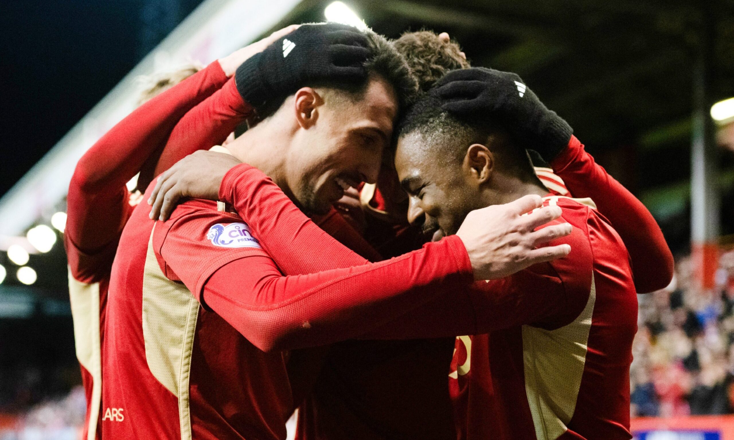 Aberdeen players with their arms around one another and resting their heads together 