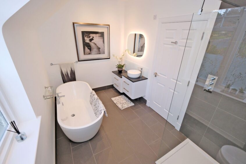 The bathroom in the house, with a stand-alone bath modern wall-mounted sink and glass cubical shower