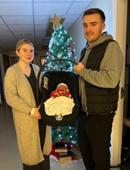 Lauren Mainland and Ross Strachan standing with their new arrival Thomas.