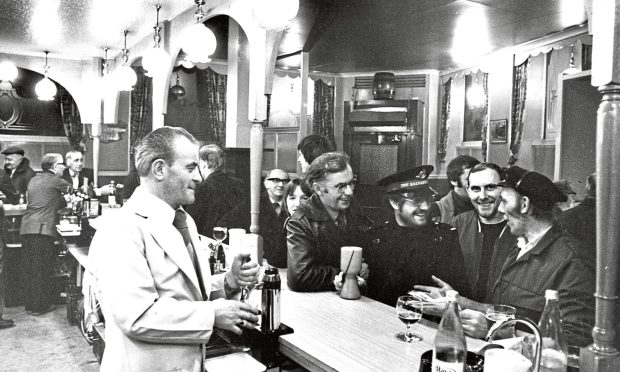 Salvationist Gordon Smith takes a break from collecting and chats to regulars at the Butchers Arms pub on George Street just before Christmas in 1980. Image: DC Thomson