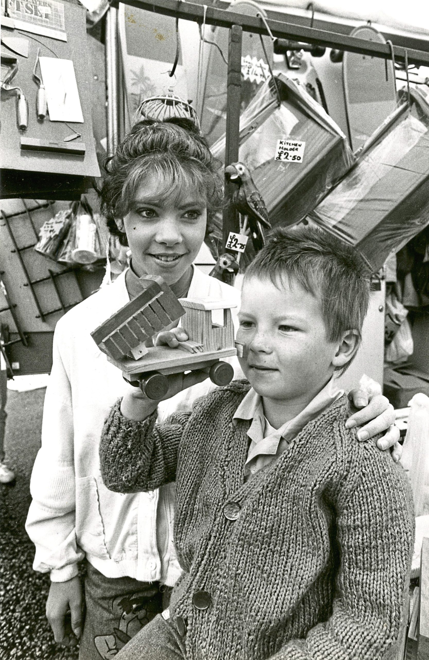 Stuart Shirran (4) holding a wooden dumper truck toy at the Timmer Market in the Castlegate in 1988. With him is assistant Vicky Stewart (16) of Torry.