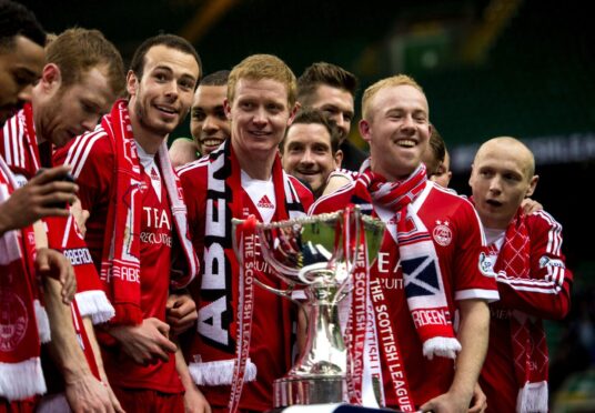 From left, Aberdeen's Andrew Considine, Barry Robson and Nicky Low celebrate with the League Cup trophy. Image: SNS.