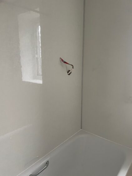 Exposed wires can be found where the shower unit should be above the bath