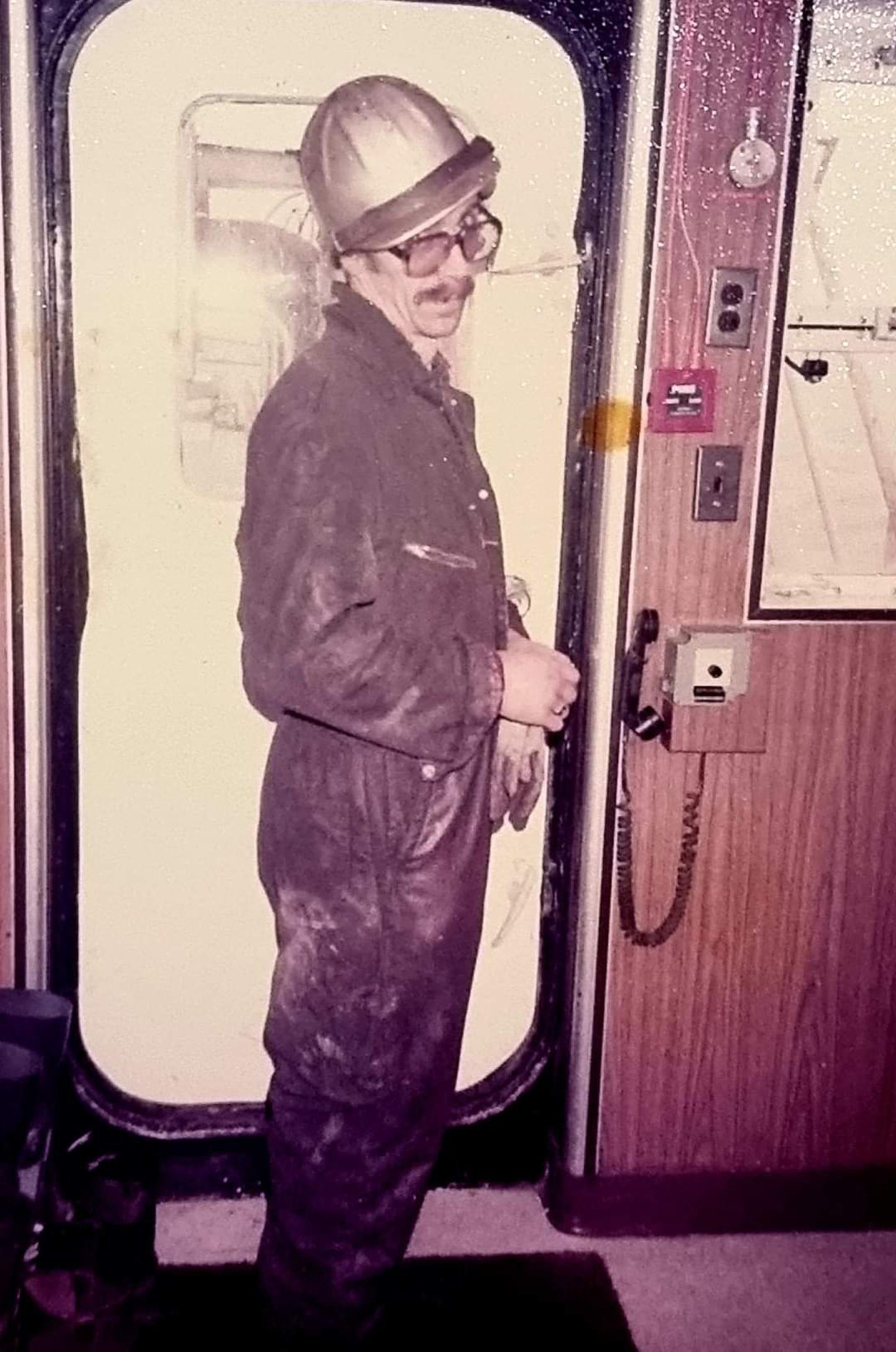Colin Adamson wearing a hard hat and boilet suit while working in the oil and gas industry, in an old photograph. 