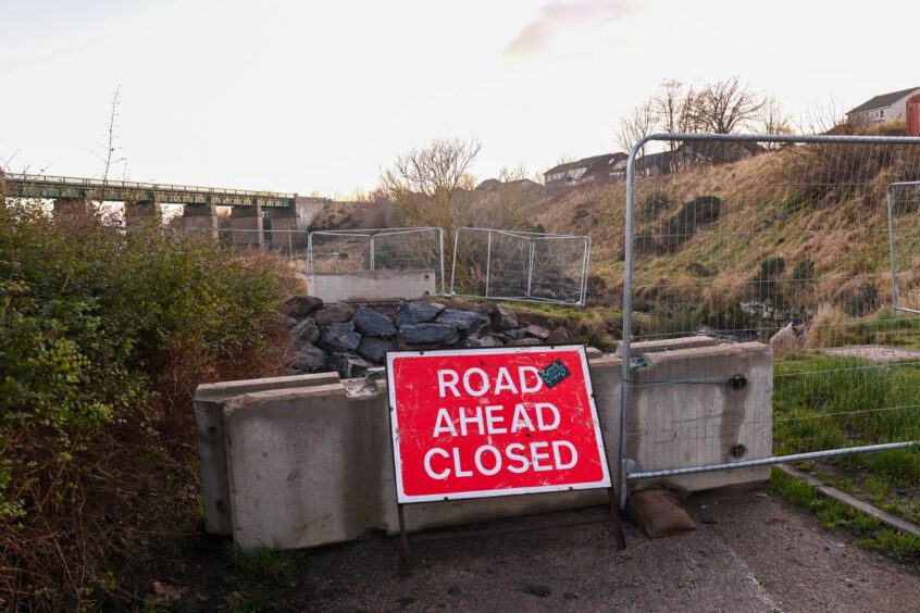 "Road ahead closed" sign at knocked down bridge.