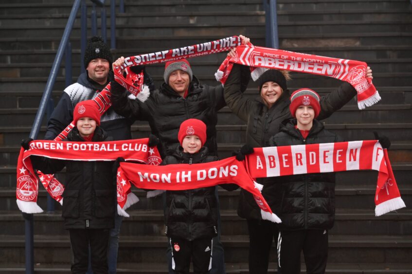 Group of Dons fans hold up their scarves.
