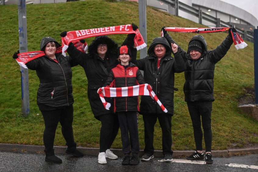 Group of fans hold up their Aberdeen FC scarves.