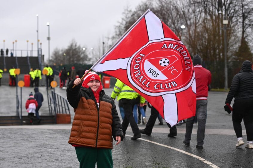 Young Dons fan waves Aberdeen flag in support.