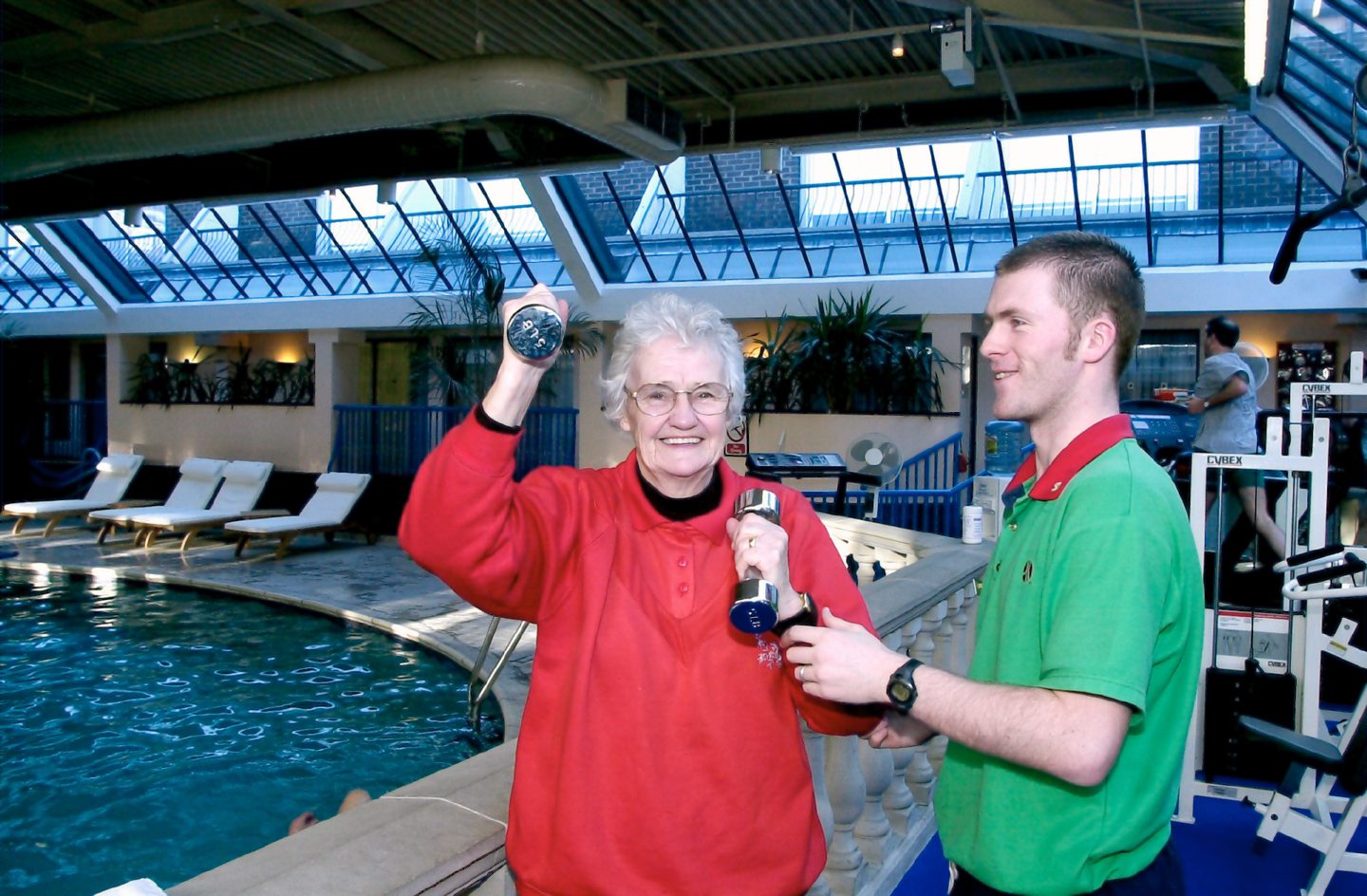 Instructor James Milne at the poolside gym in the Marriott Hotel with an elderly woman holding small weights