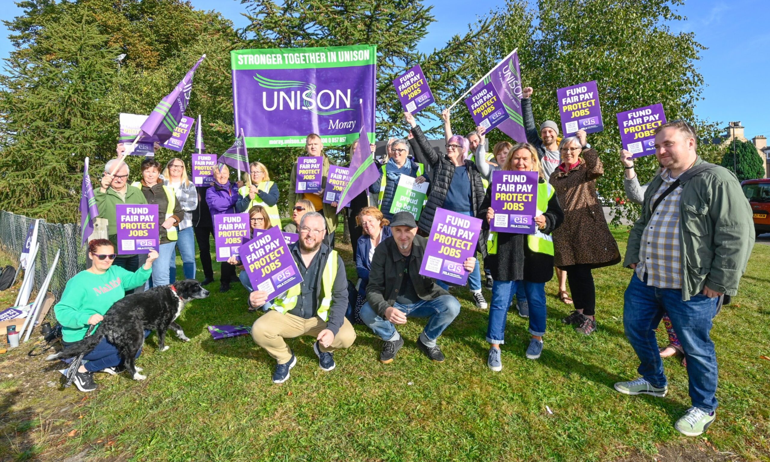 Moray UHI staff on picket line waving Unison flags and banners. 