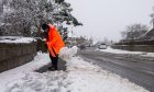 A man clears snow from the sidewalk in Newmachar. Image: Kath Flannery/DC Thomson