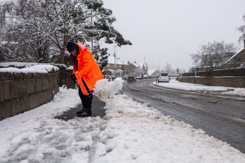 A man clearing the paths of snow in Newmachar