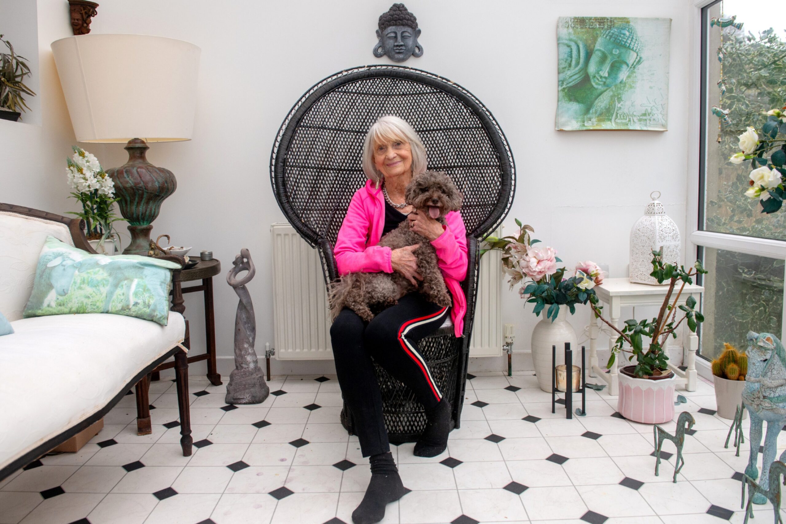 Jeane sitting on a large wicker chair with her dog ralph