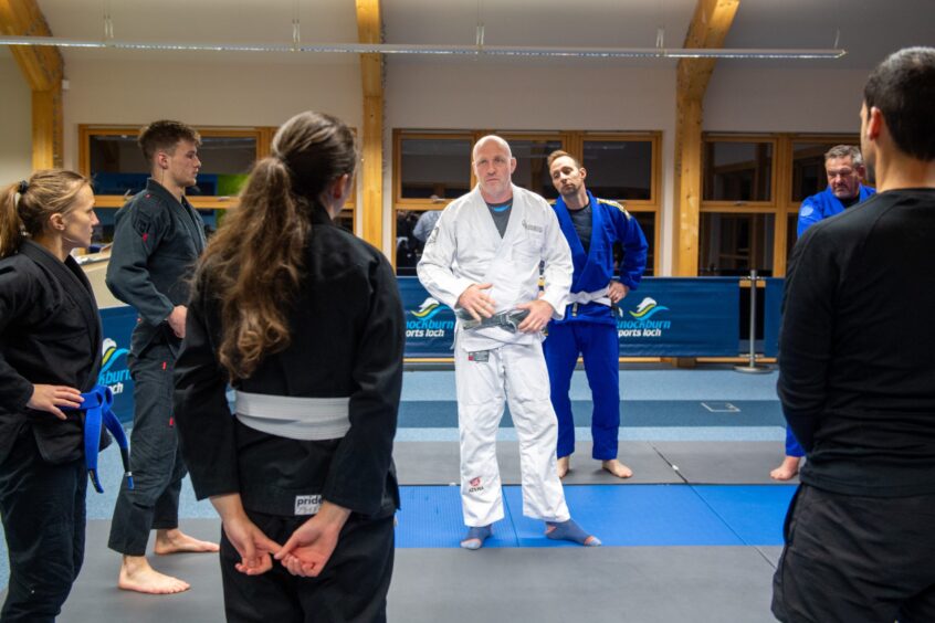 Peter Richardson the BJJ instructor standing in the middle of the mats with others gathering round. 