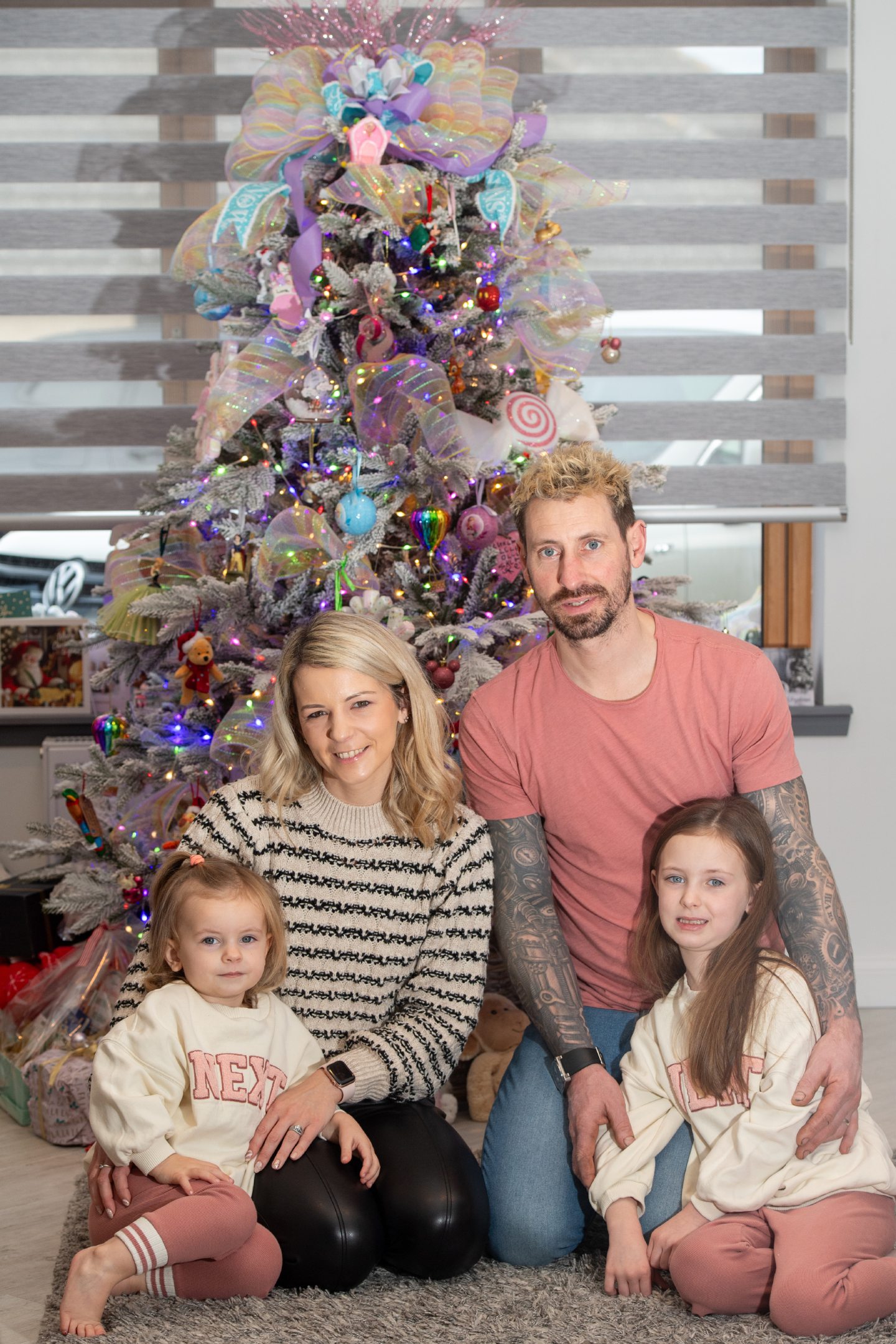 Honest Mummy blogger Carla Lawrence sits in front of her Christmas tree with her family