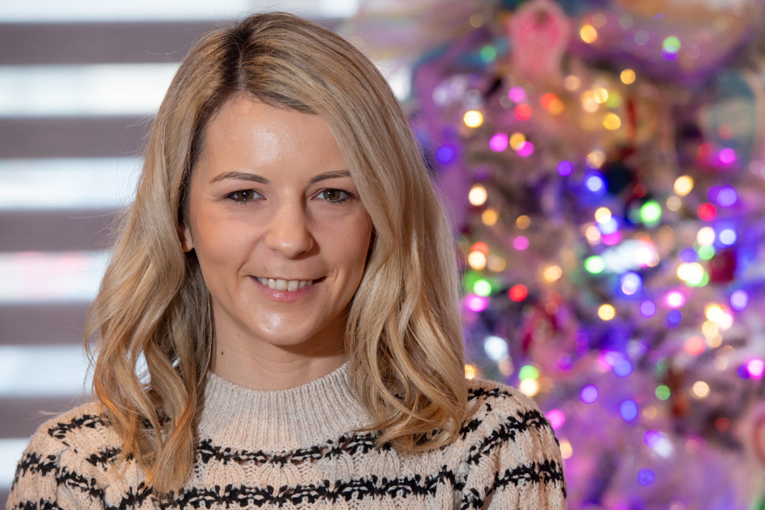 Honest Mummy blogger Carla Lawrence stands in front of her Christmas tree
