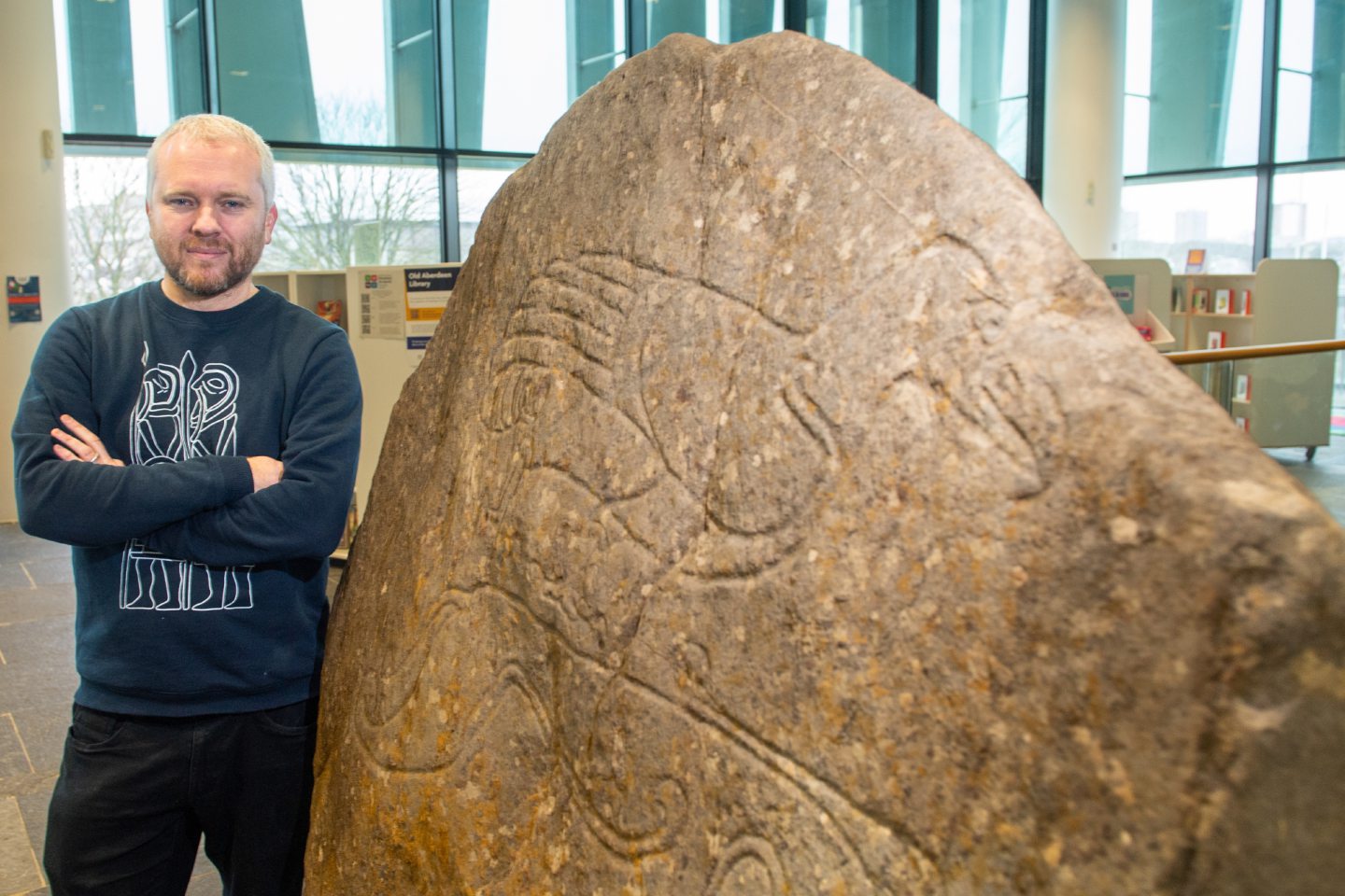 Gordon Noble standing with a carving in a stone